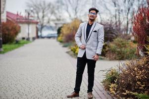 Stylish indian man with bindi on forehead and glasses, wear on suit posed outdoor. photo