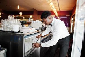 African american bartender at bar picks up ice. Alcoholic beverage preparation. photo