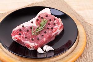 Raw red sirloin steak with rosemary, garlic , pepper photo