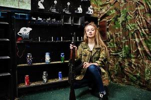 Girl with machine gun at hands on shooting range. photo