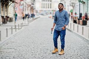 Stylish indian beard model man in casual clothes posed outdoor at street of India. photo