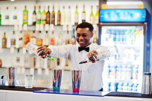 camarero afroamericano trabajando detrás del bar de cócteles. preparación de bebidas alcohólicas. foto