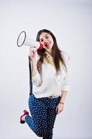 Portrait of a young woman in blue trousers and white blouse posing with megaphone in the studio. photo