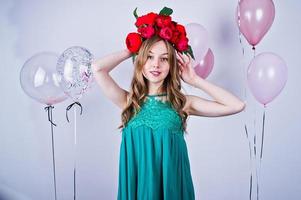 chica feliz con vestido verde turquesa y corona con globos de colores aislados en blanco. celebrando el tema del cumpleaños. foto