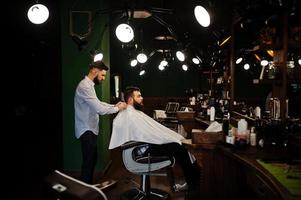 apuesto hombre barbudo en la barbería, peluquero en el trabajo. foto