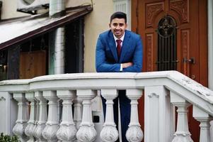 Elegant indian fashionable man model on suit posed at winter day leaned on the railing. photo