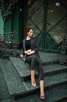 A tall leggy young beautiful and elegant model woman at formal wear posed on stairs. photo