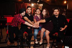 grupo de amigos indios sentados en el lounge bar, divirtiéndose y descansando. manos juntas foto