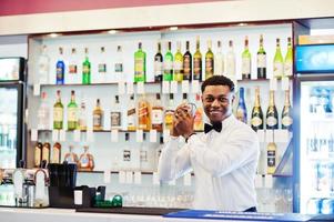 African american bartender at bar with shaker. Alcoholic beverage preparation. photo