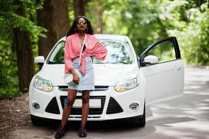 African american woman posed against white car in forest road. photo