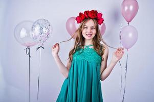 Happy girl in green turqoise dress and wreath with colored balloons isolated on white. Celebrating birthday theme. photo