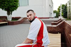 Young brutal bearded muscular man wear on white sport suit with red shirt. photo