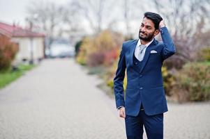 Stylish beard indian man with bindi on forehead, wear on blue suit posed outdoor. photo