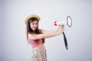 retrato de una hermosa joven en traje de baño y sombrero habla por megáfono en el estudio. foto