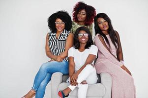 Happy brightful positive moments of four african girls. Having fun and smiling on chair against white empty wall. Lovely moments of four best friends. photo