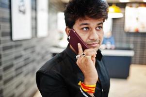 Indian man speaking on mobile phone while waiting for his order in the fast food cafe. photo