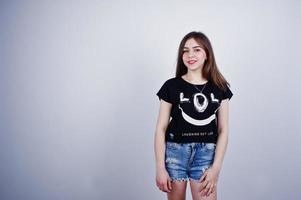 Portrait of an attractive girl in black t-shirt saying lol and denim shorts posing in the studio. photo