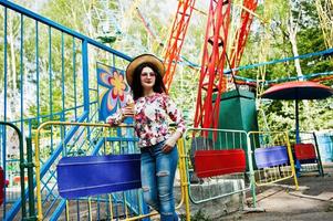 Portrait of brunette girl in pink glasses and hat with ice cream at amusement park. photo