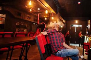 Asian man smoke hookah and having rest at lounge bar. photo