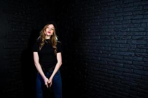 FBI female agent in cap and with gun at studio against dark brick wall. photo