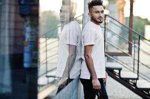 hombre de barba india con estilo en camiseta rosa. modelo india posó al aire libre en las calles de la ciudad contra el espejo de la ventana. foto