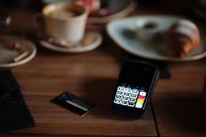 Contactless credit card and payment terminal at table in cafe. photo
