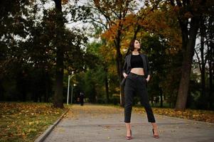 A tall leggy young beautiful and elegant model woman at formal wear posed at autumn background. photo