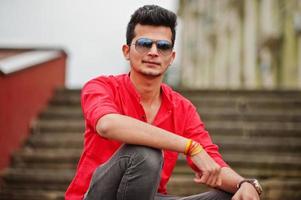 Indian man at red shirt and sunglasses posed outdoor. photo