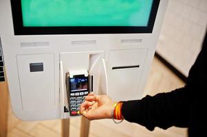 Hands of man customer at store place orders and pay by credit card through self pay floor kiosk for fast food, payment terminal. photo