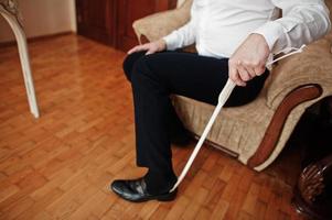 Man puts on classic black shoes with a wooden shoe spoon. photo