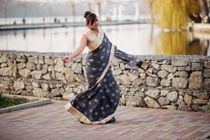 elegante morena chica india del sur de asia en sari bailando al aire libre. foto