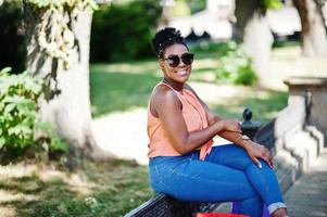 Casual african american girl with colored shopping bags walking outdoor. Stylish black woman shopping. photo