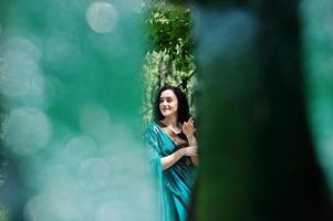 Portrait of beautiful indian brumette girl or hindu woman model on bridge. Traditional Indian costume lehenga choli. photo