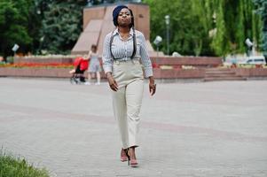 Stylish african american business woman at trousers with suspender and blouse posed outdoor. photo