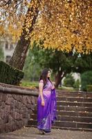 Indian hindu girl at traditional violet saree posed at autumn street. photo