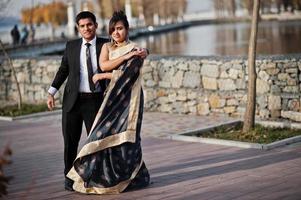 elegante y de moda amigos indios pareja de mujer en sari y hombre en traje bailando juntos al aire libre. foto