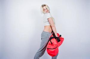 Blonde sporty girl with big sport bag posed at studio against white background. photo