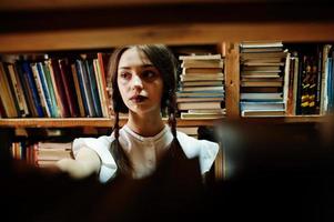 Girl with pigtails in white blouse at old library. photo