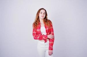 Young girl in red checked shirt and white pants against white background on studio. photo