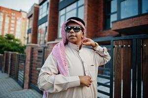 hombre de negocios árabe del medio oriente posó en la calle contra un edificio moderno con gafas de sol. foto