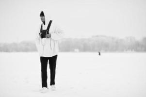 Elegante hombre afroamericano de estilo urbano con capucha rosa posado en un lago congelado en invierno. foto