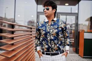 Attractive and handsome stylish indian man wear on shirt and sunglasses standing in the terrace of modern lounge cafe at his work break. photo