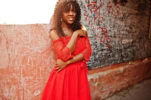 elegante mujer rizada afro francia de moda posó en el día de otoño con vestido rojo. modelo de mujer africana negra. foto