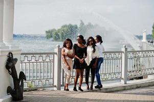 Group of four african american girls having fun against lake with fountains. photo