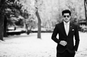 Elegant indian macho man model on suit and pink tie, sunglasses posed on winter day. photo