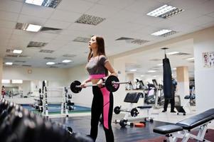 Young brunette sexy slim girl doing workout at gym. photo