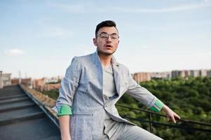 hombre macho con estilo soñador en traje gris y gafas posadas en el techo. foto