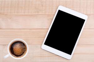 café y teléfono móvil o tableta con fondo de madera de maqueta de pantalla en blanco foto