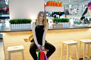 chica con bolsas de compras en la silla sentada del centro comercial. foto