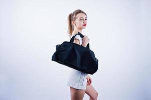 Amazing fit sexy body brunette caucasian girl posing at studio against white background on shorts and top with black sport bag. photo